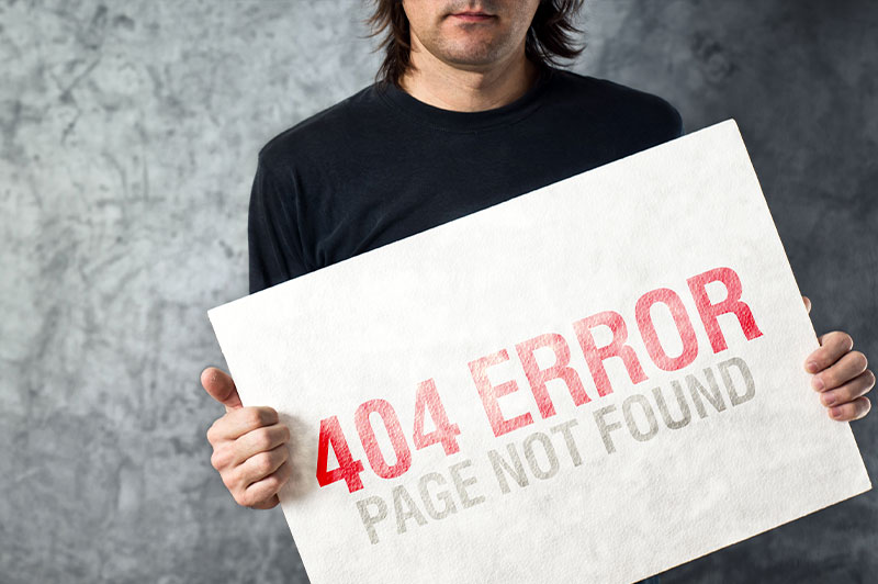 Eine Person hält ein Schild hoch, auf dem "404 Error Page Not Found" steht