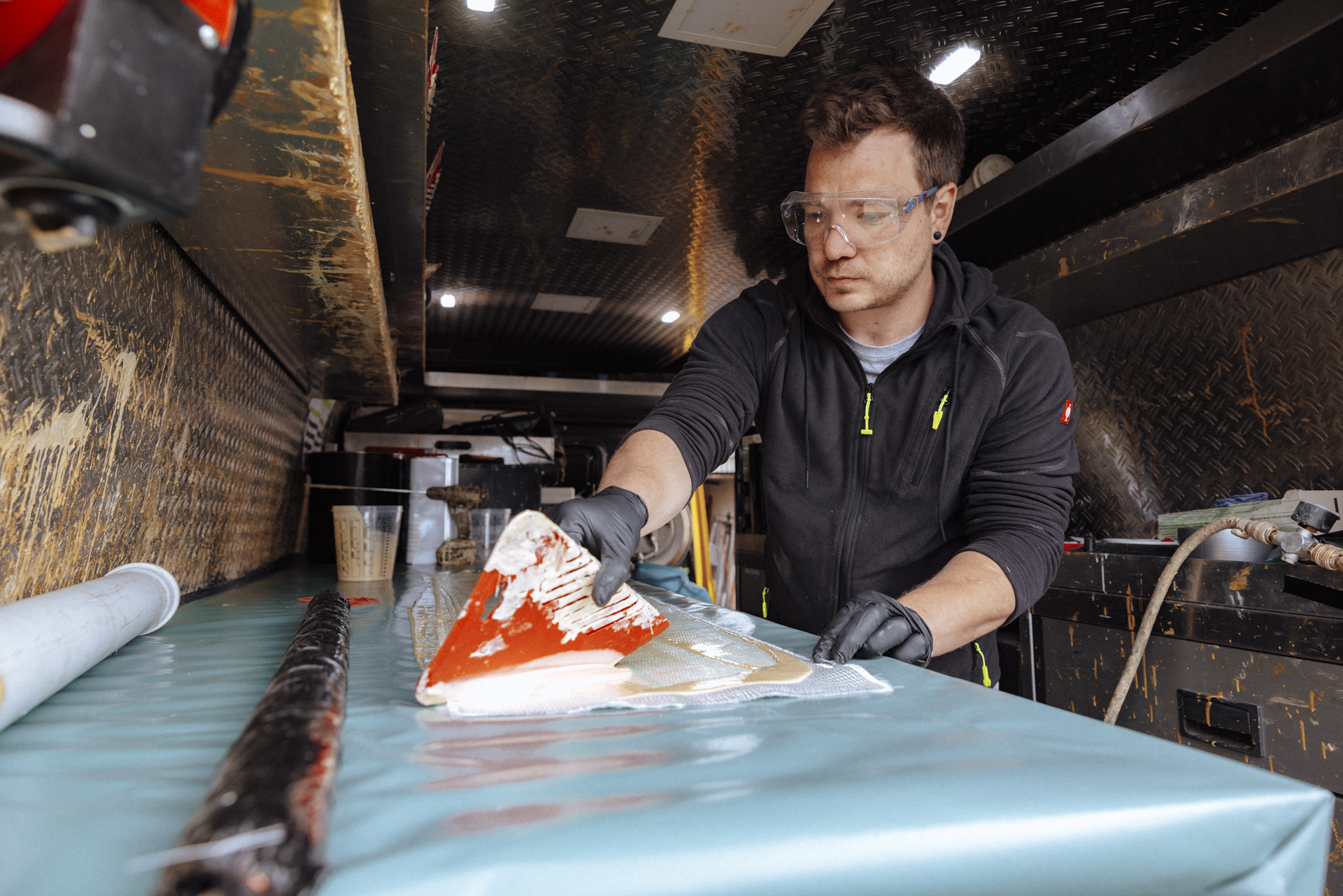 Mann trägt Harz auf eine Folie mit einem Spachtel auf