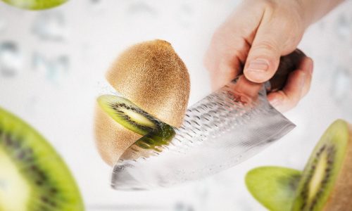 Eine Kiwi wird in Nahaufnahme mit einem Küchenmesser halbiert