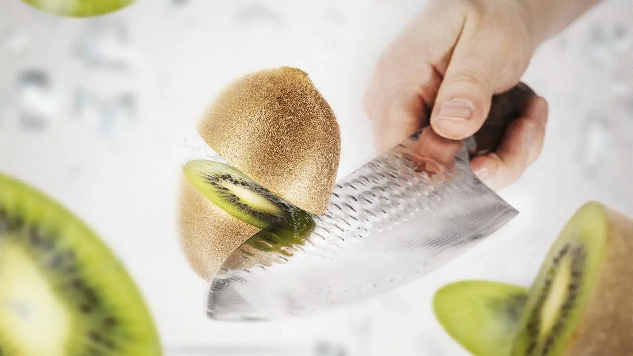Eine Kiwi wird in Nahaufnahme mit einem Küchenmesser halbiert