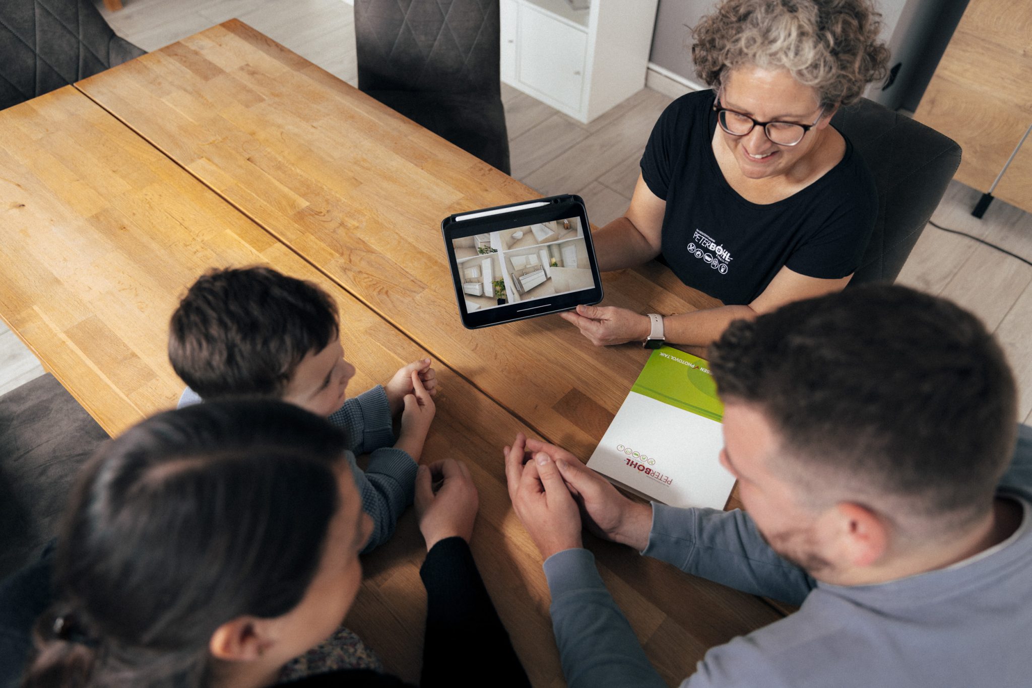 Eine Beraterin zeigt einer Familie etwas an einem Tablet