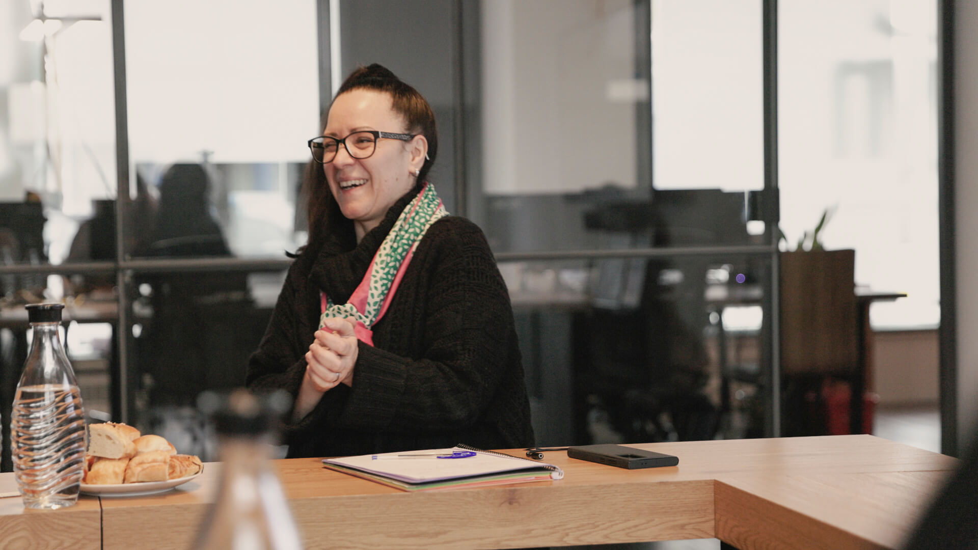 Eine Person sitzt angeregt an einem Tisch vor einem Notizblock