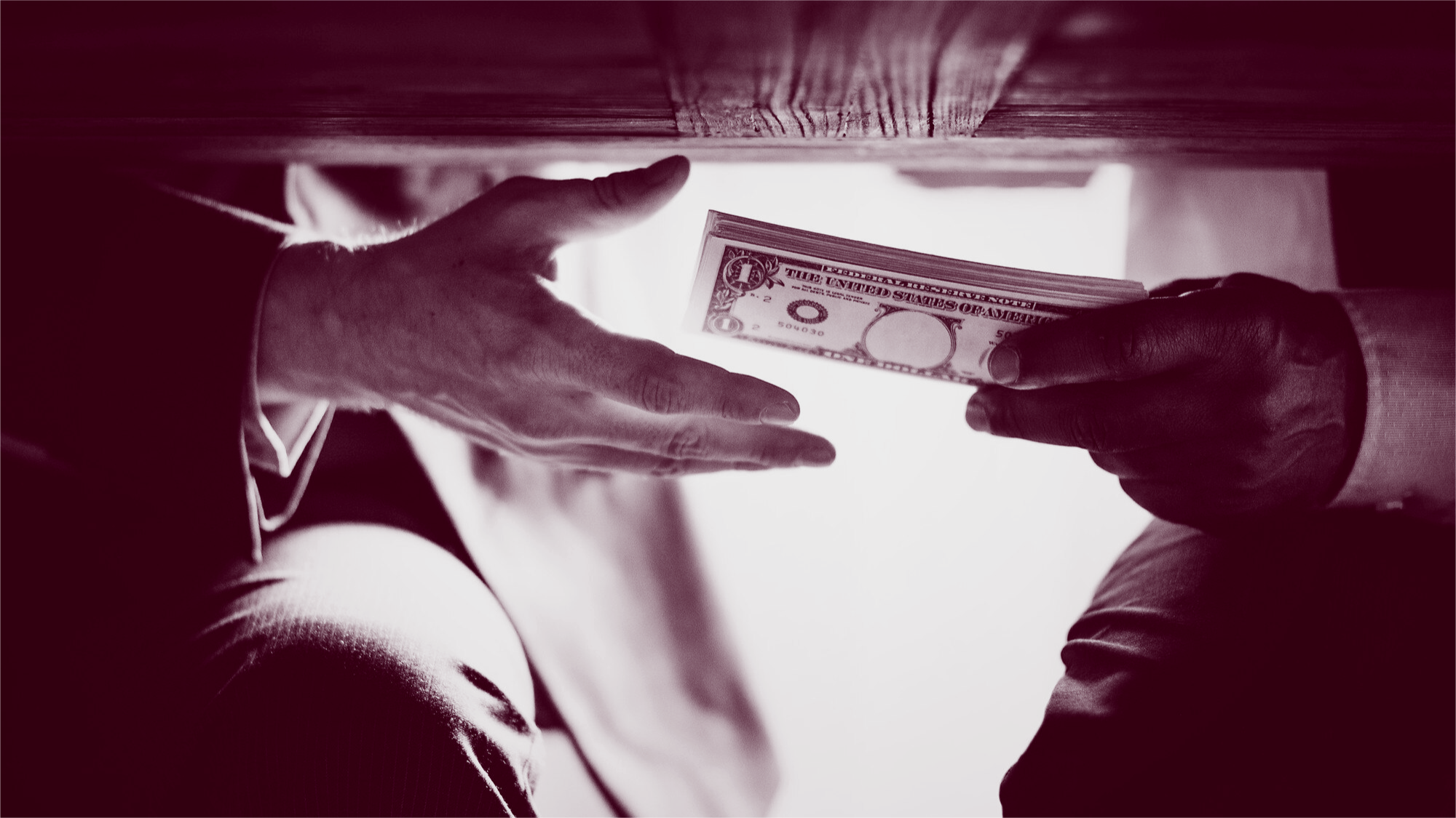 Geld wechselt unter einem Tisch die Hand. Symbolbild für bezahlte Links im Black Hat SEO.