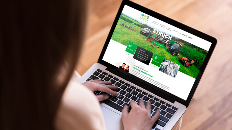 Eine Frau sitzt an einem Laptop, der die Homepage von Struck Garten- und Landschaftsservice zeigt