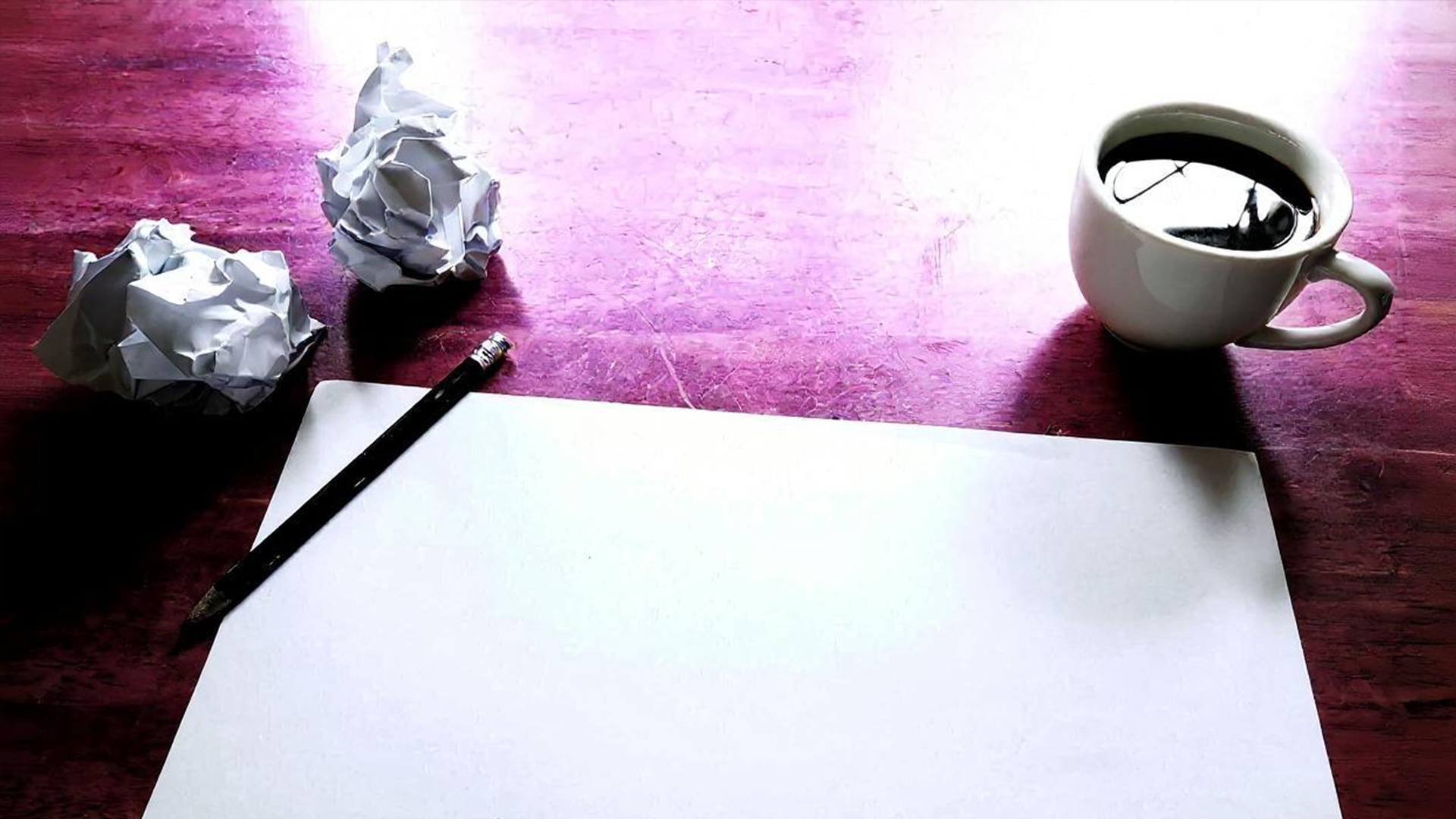 Origineller Content ist wichtig bei Shop SEO - so wie der, der auf diesem Blatt Papier entsteht, umrandet von Kaffeetasse und zusammengeknüllten Papier.